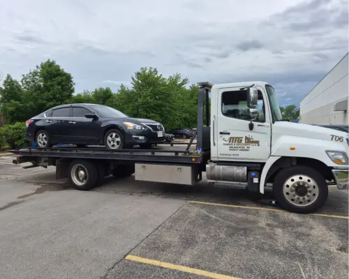 flatbed tow truck carrying a black car